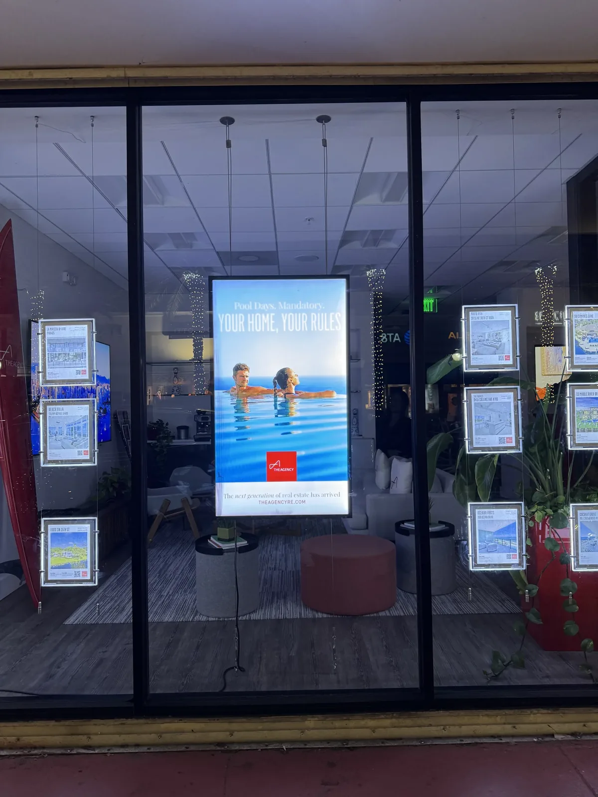 Real estate office window with a portrait digital display among listing frames